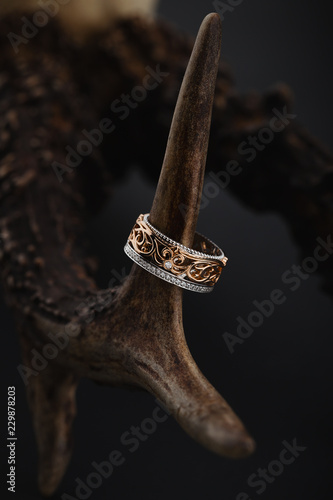 Pink gold and white gold ring with floral pattern on black background photo