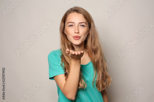 Bild auf Leinwand Portrait of beautiful young woman blowing kiss on light background