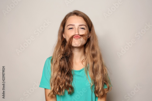 Portrait of funny young woman on light background © Pixel-Shot