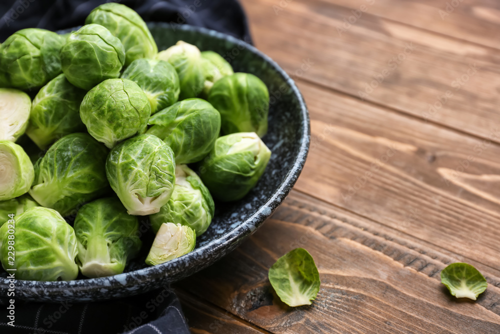 Plate with fresh brussels sprouts on wooden table, closeup Plate with fresh brussels sprouts on wooden table, closeup