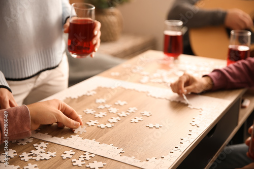 Group of people assembling puzzle on wooden table