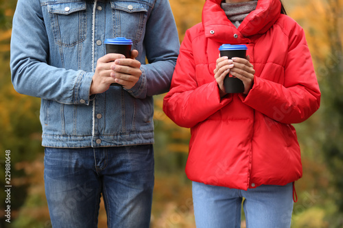 Loving young couple with coffee on romantic date in autumn park