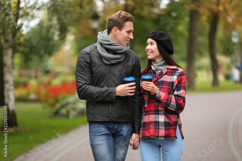Loving young couple with coffee on romantic date in autumn park