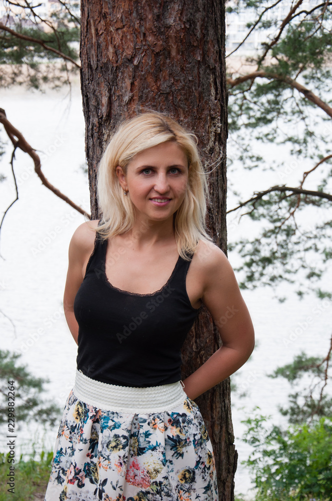 Closeup, pretty smiling blonde in black t-shirt posing on camera