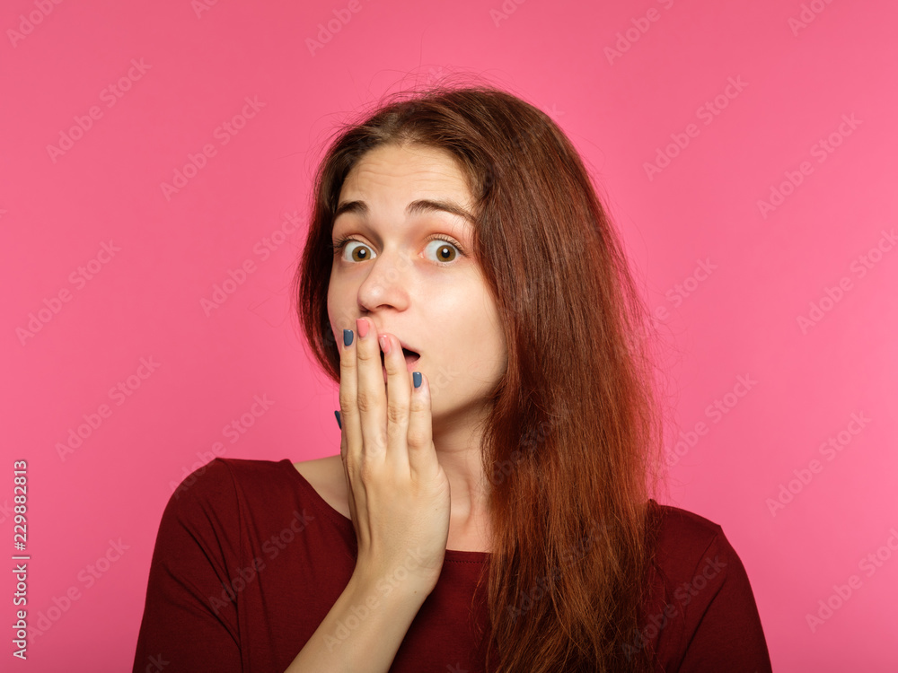 surprised shocked astonished amazed girl covering mouth with hand. unbelievable news. young beautiful woman on pink background. emotional facial expression. surprised shocked astonished amazed girl covering mouth with hand. unbelievable news. young beautiful woman on pink background. emotional facial expression.