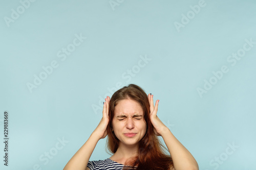 don't want to hear it. rejection refusal and denial. young woman covering ears with hands. portrait of a girl with tightly shut eyes on blue background. photo