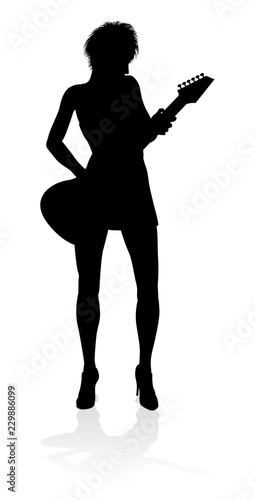 A female guitarist musician in detailed silhouette playing her guitar musical instrument.