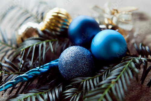 Blue, frozen, gold,  silver Christmas decor small baubles decorations with holly tree leaves and wooden rustic background. photo