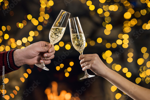 Photography Couple clink champagne glasses at night on bright holiday
