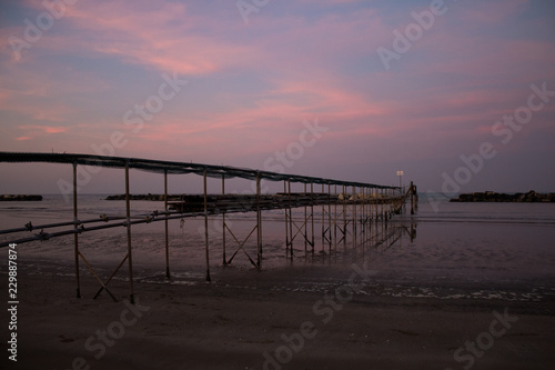 Peaceful evening on the shore  with scenic pink sunset reflected on water ant metallic pier  adriatic sea