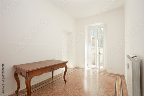 White room with wooden table in renovated apartment in a sunny day