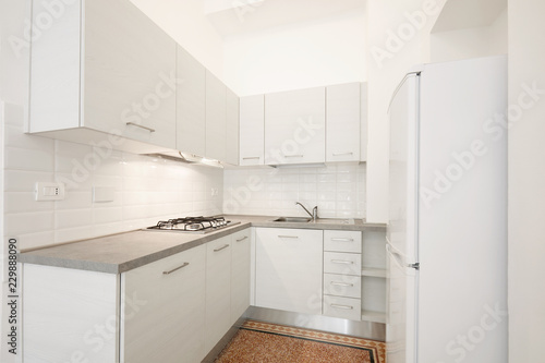 New, white wooden kitchen with gray stone top in ancient renovated apartment interior
