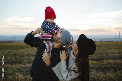 The dad holds his face in his arms with his mother. Photo session with family at sunset.