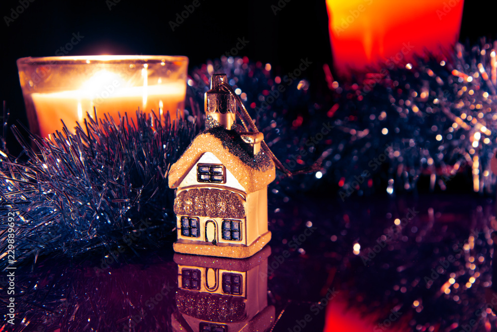 Fototapeta premium Colorful snow-covered houses with romantic reflections and Christmas candles atmospheric lights on a blurred background with bokeh effect. Christmas and New Year holiday background concept.