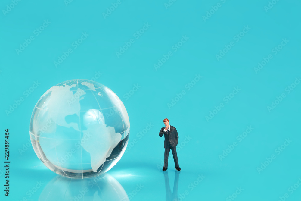 Miniature people: businessman standing on earth with blue background