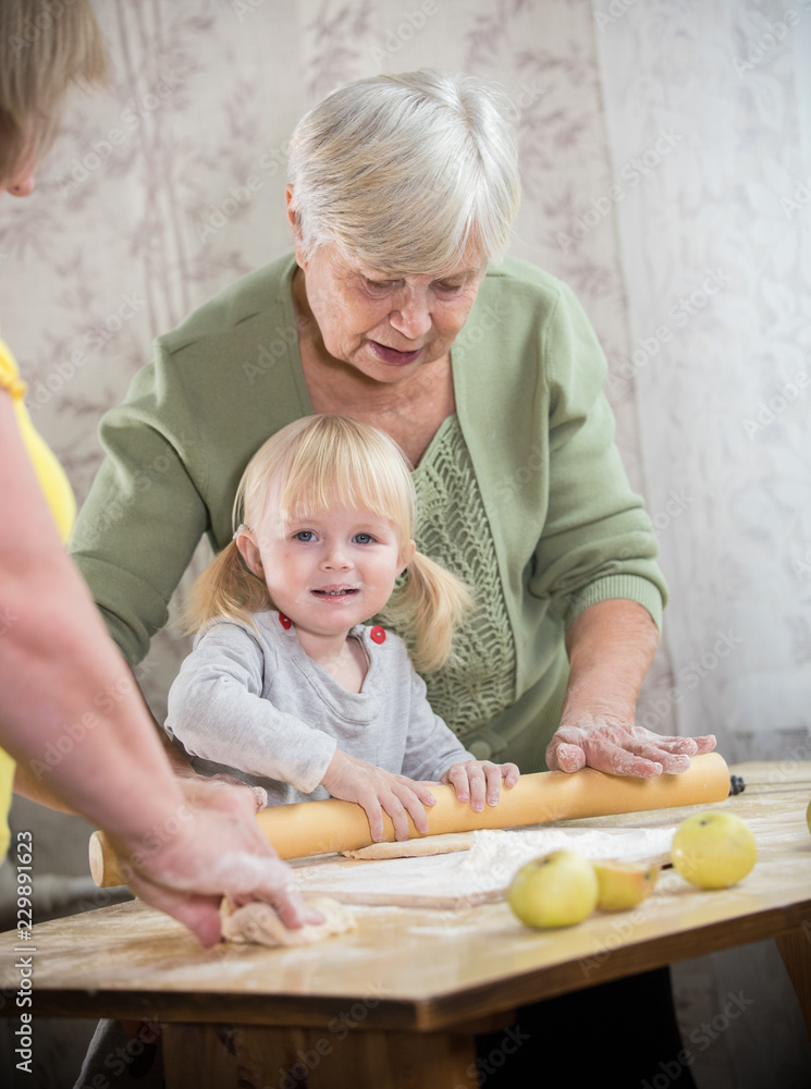 Obraz premium An old lady making little pies with a little girl. Girl looking in the camera