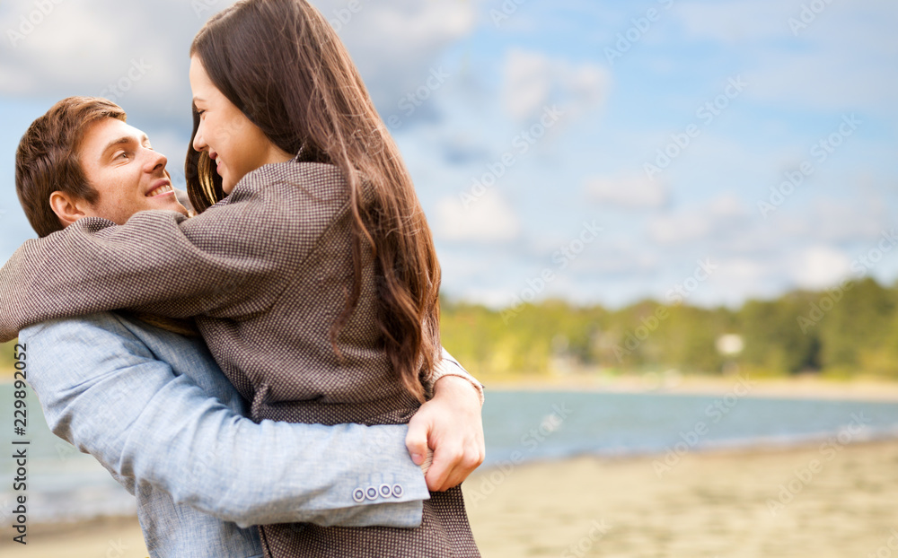 love, relationships and people concept - happy teenage couple hugging over autumn beach background