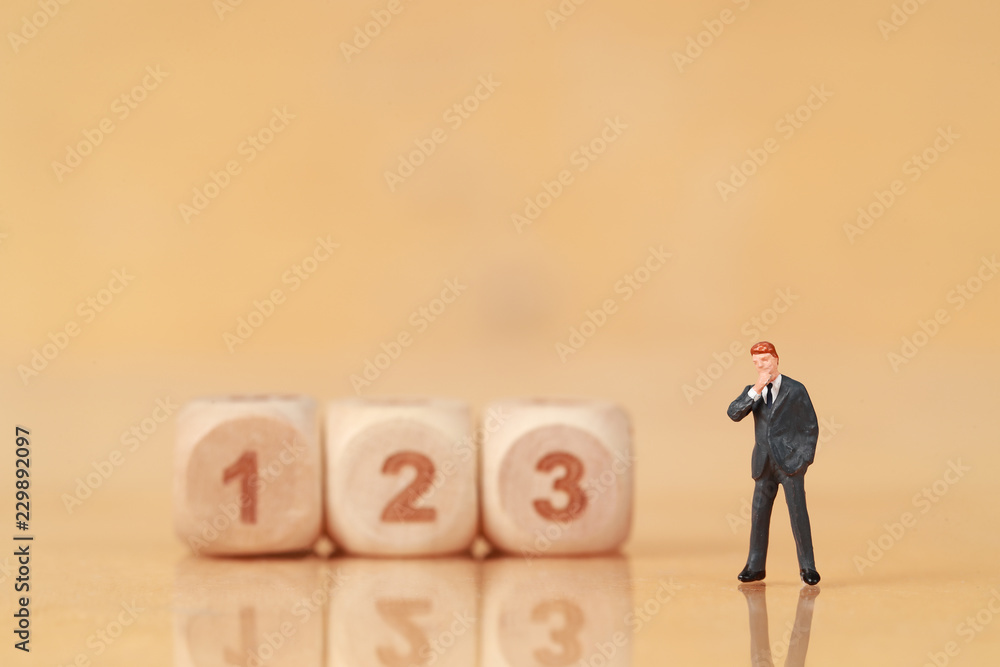 Miniature people: businessman standing with wooden podium using as background (Financial and Business competition concept) Miniature people: businessman standing with wooden podium using as background (Financial and Business competition concept)