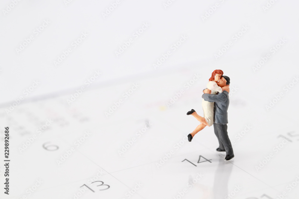 Miniature people: a couple standing on calendar at 14 February , meaning of love. Miniature people: a couple standing on calendar at 14 February , meaning of love.