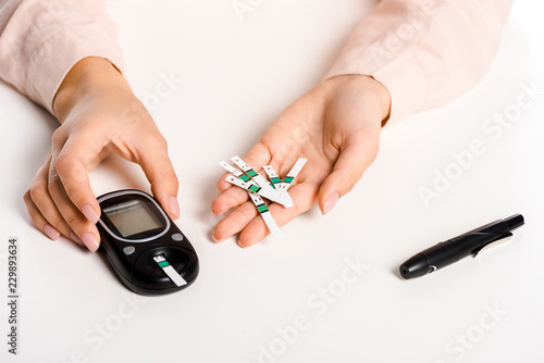 Принти на полотні cropped image of woman holding glucometer and strips isolated on white, diabetes