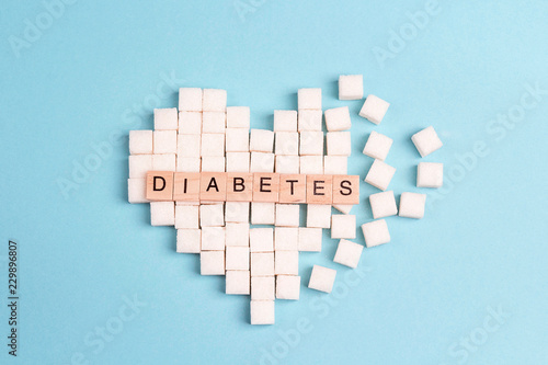 Broken heart made of sugar cubes with inscription diabetes on a blue background. photo