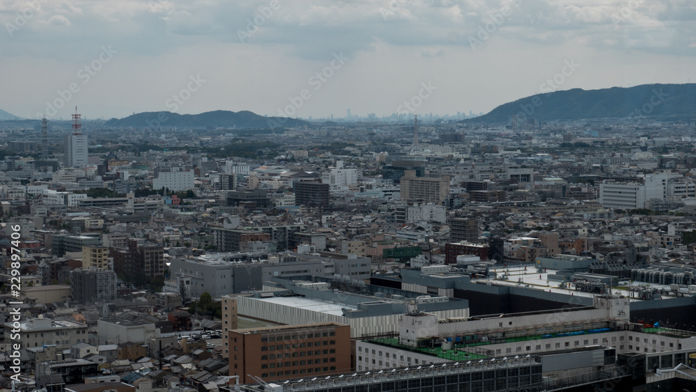 Aerial shots of the city of Kyoto. Skyscrapers and buildings expand out into the distance of the Japanese city as a stormy sky and clouds form over the cityscape.