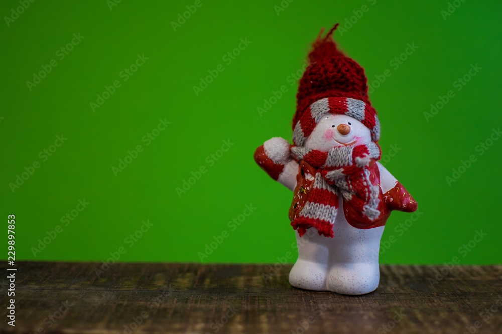 Closeup of snowman with a red scarf and white scarf throwing a snowball and a snowsled