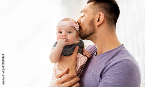 family, fatherhood and people concept - close up of happy father kissing little baby daughter photo