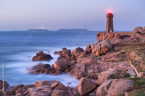 twilight above rocks in blurre water and lighthouse in Bretagne in France © sergejson
