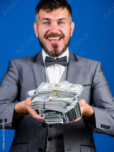 Get cash easy and quickly. Cash transaction business. Man happy winner rich hold pile of dollar banknotes blue background. Win lottery concept. Easy cash loans. Businessman got cash money photo