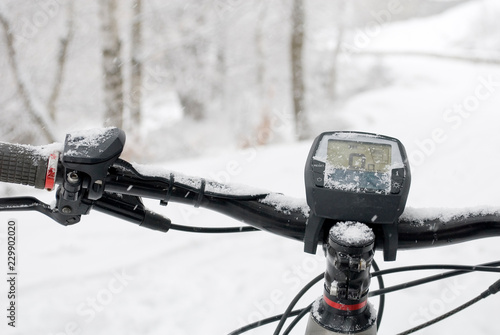 detail of handlebars and display of an electric bicycle, e-bike, ebike, mountain forest during snow storm, blizzard, sport, end of winter, cold, alps, adventure, Piedmont, Italy