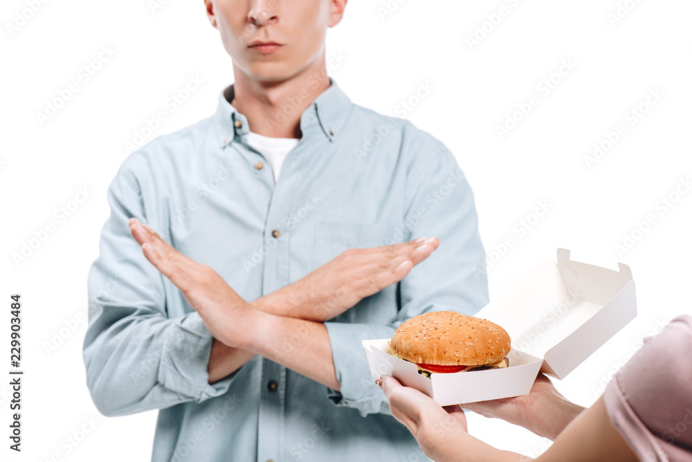 cropped image of man showing no sign to woman proposing burger isolated on white cropped image of man showing no sign to woman proposing burger isolated on white