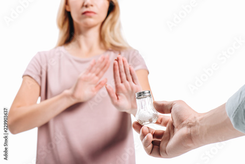cropped image of woman rejecting saltcellar with powdered salt isolated on white