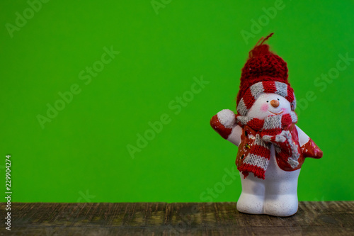 Closeup of snowman with a red scarf and white scarf throwing a snowball and a snowsled photo