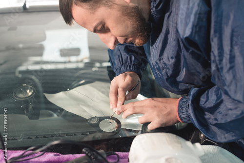 Close up Automobile glazier worker fixing and repair windscreen or windshield of a car in auto service station garage photo