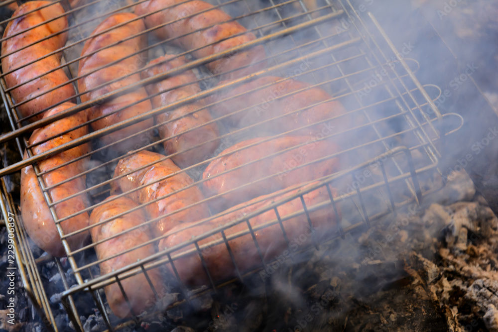 Grilling sausages on barbecue grill. BBQ in the autumn forest. Close-up. Soft focus