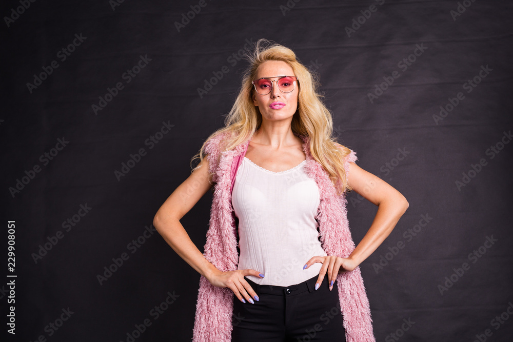 Fashion and beauty concept - Close up portrait of blond model dressed in white shirt and pink cardigan over dark background. Fashion and beauty concept - Close up portrait of blond model dressed in white shirt and pink cardigan over dark background.