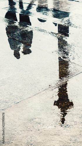 Reflection of couple in wet pavement front of Nelson's Column, Traflagar Square, London, UK