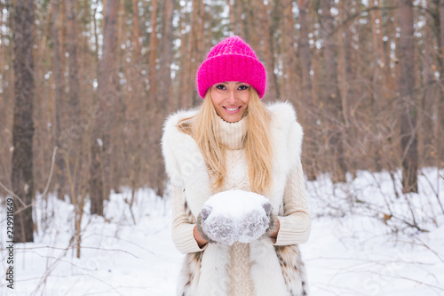 Winter and people concept - Beautiful blonde young woman make snowball in snowy park © satura_
