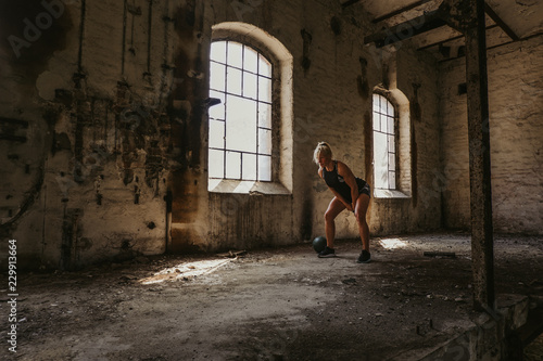 Athletic woman swinging kettlebell  in an old building © sasamihajlovic