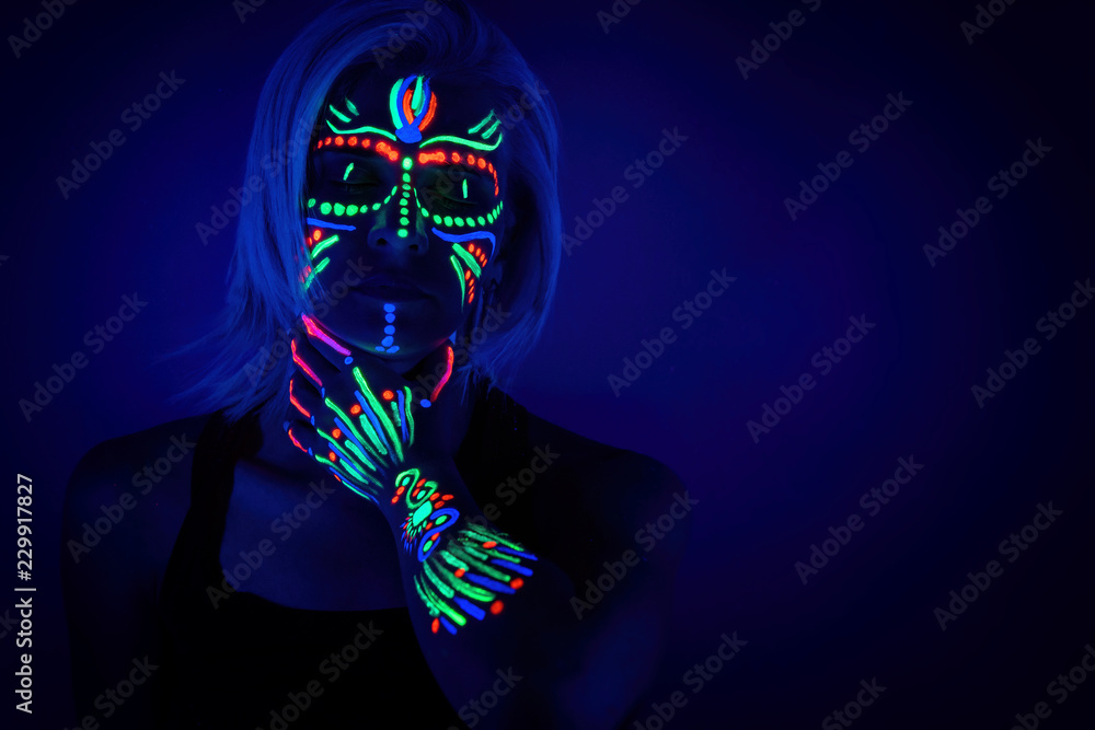Portrait of woman with ethnic pattern, neon makeup in ultraviolet light.  Body Art design of female posing in UV, painted face and hand, colourful  make up Stock Photo | Adobe Stock
