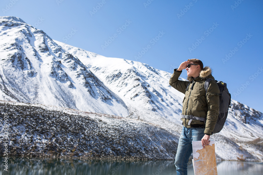 man stands on the background of mountains and looks into the distance. A man holds a card in his hand