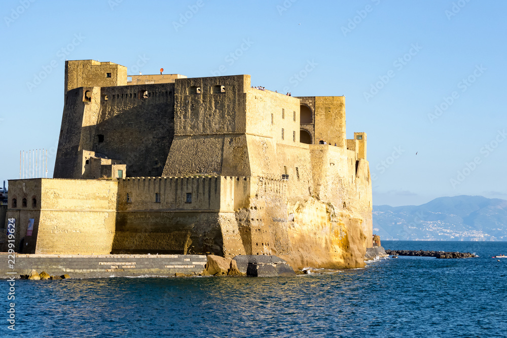 Landscape view of the gulf of Naples in Italy with a medieval castle in the fore ground, a landmark of the city, in front of the mountains in the distance, good day with perfect weather