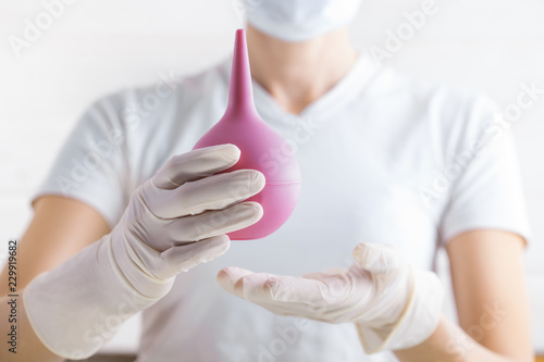 Enema in the doctor's hand on the white background.