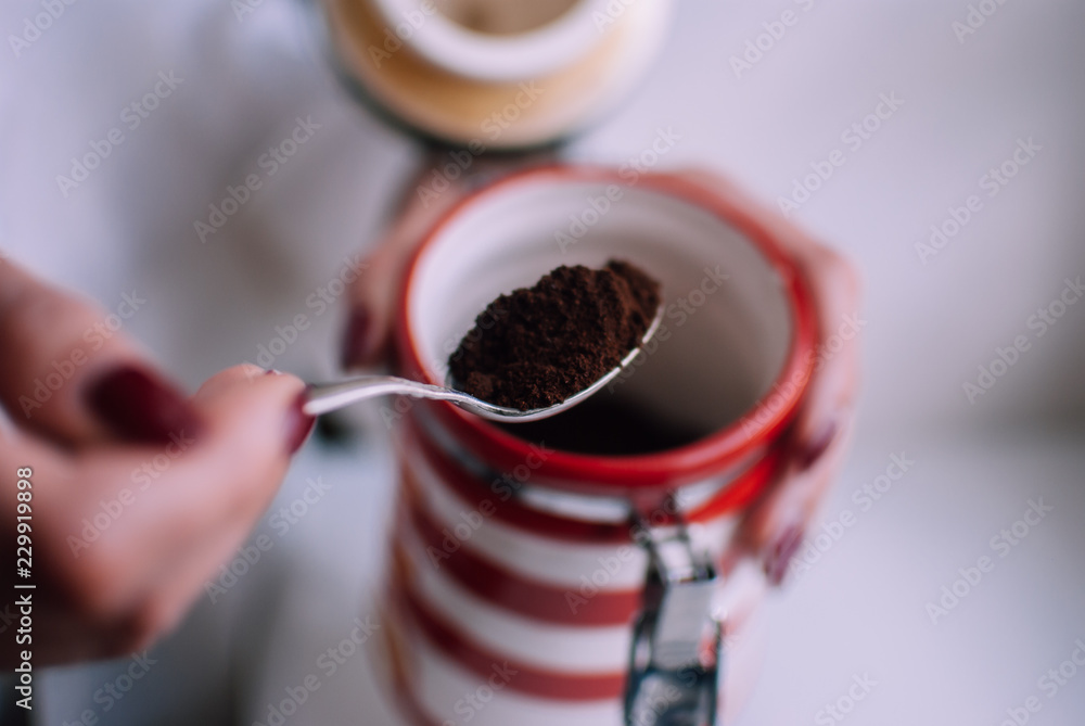 Girl holding a coffee spoon in her hands against white background. High contrast photo of a cozy morning atmosphere. Perfect way to start a day with energy and joy.