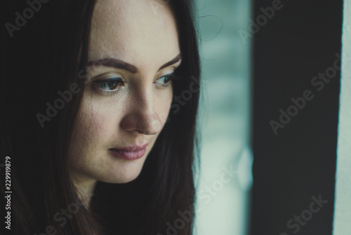 Portrait of a caucasian white girl with dark black eyes looking in the distance. Soft pale skin. Long-haired brunette. Close-up