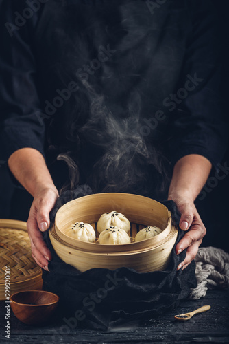Woman presenting dim sum dumplings in steamer photo