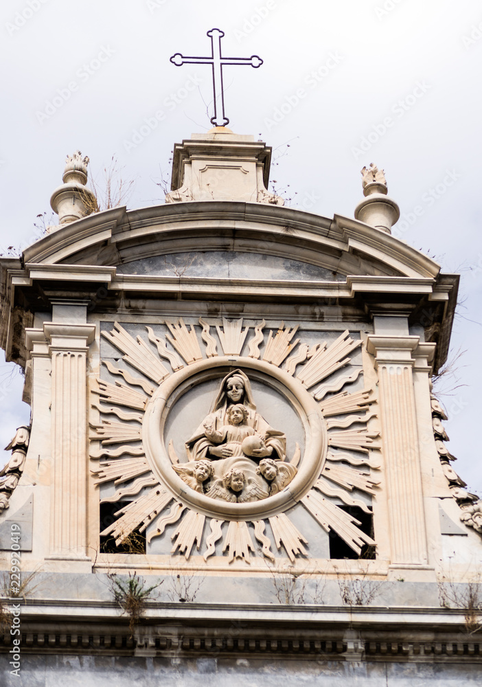 Detail of a church front that represent Saint Mary and the Baby with some little angels in Naples, Italy