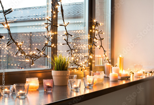 hygge, decoration and christmas concept - candles burning in lanterns and fes...