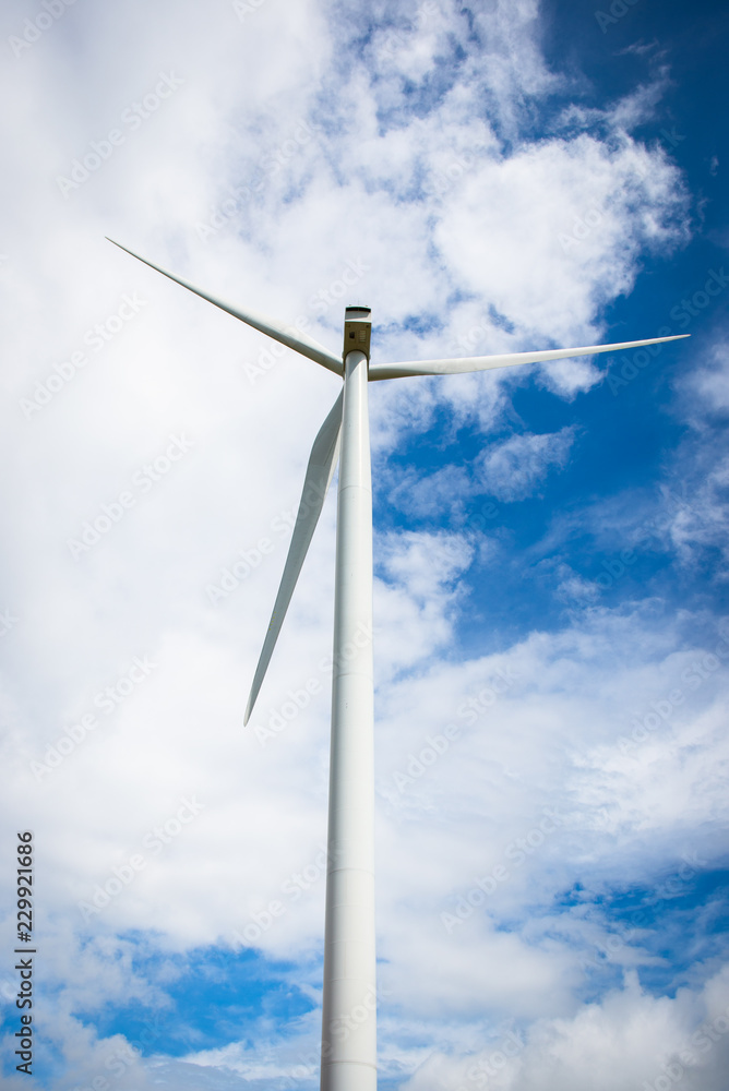 The image behind the wind turbine for electricity on a cloudy day in the blue sky. The image behind the wind turbine for electricity on a cloudy day in the blue sky.